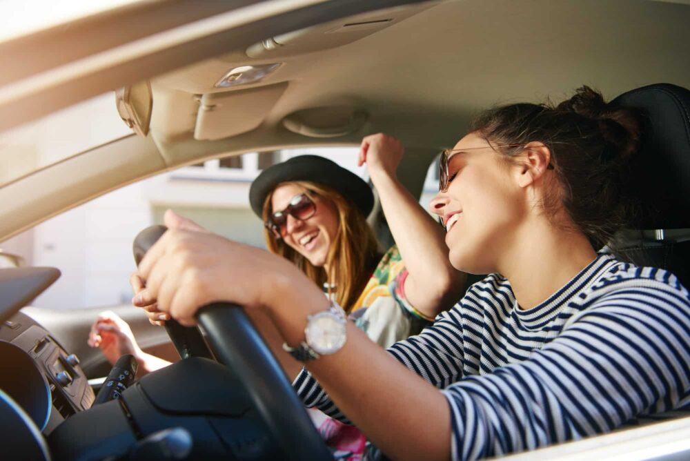 Two young woman singing along in the car